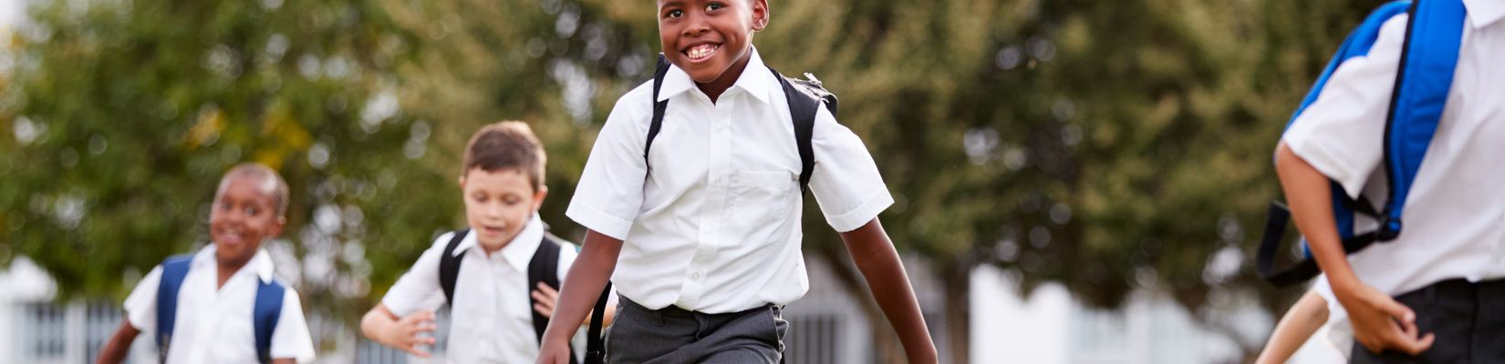 Primary school pupils in uniform running across a field