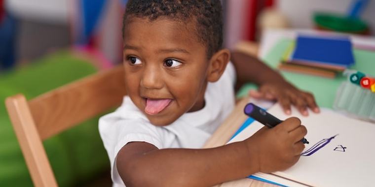 A young boy drawing at a classroom table